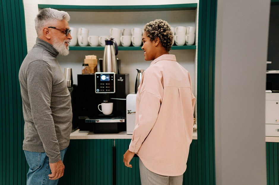 Two people standing in front of a MCRVending Coffee Machine in a modern kitchen.